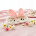 Handcrafted white crochet bunny eyeglasses holder with pink ears on pastel pink surface with spring flowers
